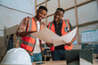 African American colleagues in safety vests review designs in carpentry warehouse 