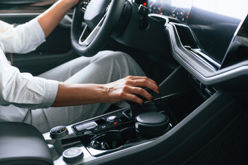 Close up view. Woman is sitting in a car and driving it