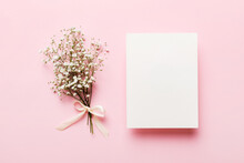 Wedding Mockup With White Paper List And Flowers Gypsophila On Colored Table Top View Flat Lay. Blank Greeting Cards And Envelopes. Beautiful Floral Pattern. Flat Lay Style
