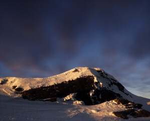 Wall Mural - Snow mountain at sunset under a blue sky with some clouds.