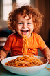 Happy boy eating tasty pasta at table in kitchen.