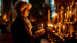Elderly woman lighting candles in church, remembering loved ones, solemn memory and tribute. Shallow field of view.