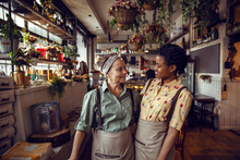 Diverse Female Cafe Workers Smiling In A Rustic Decorated Coffee Shop