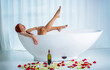Girl takes a bath with foam and beautiful legs. Woman in a bath with foam drinking wine, champagne. Sexy girl relax in spa treatments. Woman holding glass of wine while taking bath with rose petals