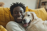 Fototapeta Przestrzenne - Young adult black man with his golden retriever dog in a living room