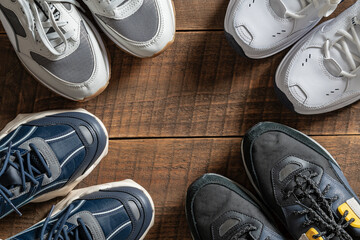 Four pairs of various sneakers on a wooden background, closeup, top view, copy space