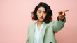 Portrait of young asian businesswoman pointing at something on pink background