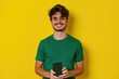 © Fotograf - A man in a green shirt holding a cell phone. Perfect for technology-related projects