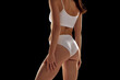 © master1305 - Back view cropped image of slim smooth female body, buttocks in underwear against black studio background. Anti-cellulite products. Concept of natural beauty, health and body care, spa, sport