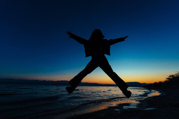 Sticker - Man jumping on lake background dark silhouette at sunset light