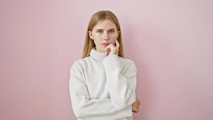 Poster - Confident and beautiful blonde girl standing proud, smiling positively at camera. hand on chin, arms crossed over pink isolated background