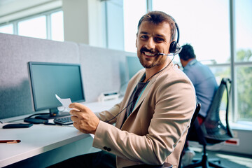 Wall Mural - Happy customer support representative at work looking at camera.