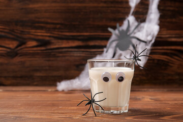 Wall Mural - Glass of milk and spiders for Halloween on wooden background