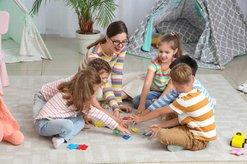 Poster - Little children with nursery teacher doing puzzle in kindergarten