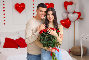 Young man proposing to his girlfriend in bedroom. Valentine's Day celebration