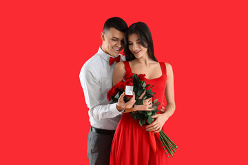 Sticker - Young engaged couple with wedding ring and bouquet of roses on red background. Valentine's Day celebration