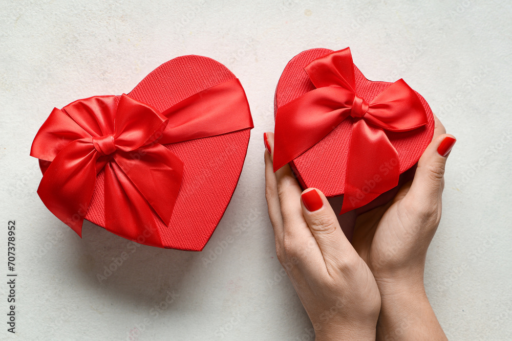Female hands with red manicure and gift boxes on white grunge background. Valentine's Day celebration