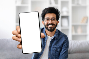 Poster - Friendly young indian man with glasses smiling while presenting blank smartphone screen