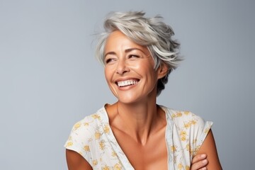Wall Mural - Portrait of a happy middle aged woman smiling at the camera over grey background