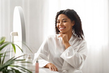 Poster - Beautiful black woman sitting at dressing table at home and touching chin