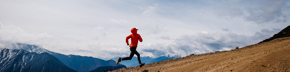 Wall Mural - Woman trail runner cross country running at high altitude mountains