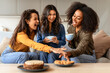 Three joyful multiethnic friends ladies share laughter over coffee indoors