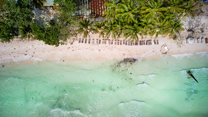 Wall Mural - Aerial view of a tropical beach with crystal clear water, and garbage in the water, palm trees, and sun loungers on a sunny day, perfect for a summer vacation concept