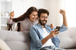 © Prostock-studio - Excited millennial indian man and woman looking at phone screen