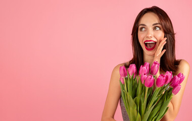 Wall Mural - Surprised and delighted young woman in a glittery silver dress holding a bouquet