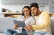 © Prostock-studio - Happy Young Indian Couple Using Digital Tablet While Relaxing On Couch