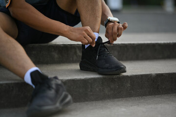 Young sporty man tying shoelaces getting ready for jogging outdoors. Healthy lifestyle concept