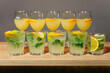 Mint Mojitos and Orange Cocktails on Wooden Bar. Refreshing mint mojitos and citrusy orange cocktails garnished with lemon slices, served on a wooden bar, perfect for summer gatherings.