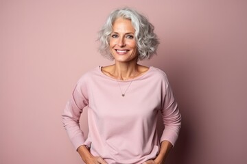 Wall Mural - Portrait of a happy senior woman on a pink background looking at the camera