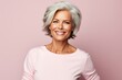 Mature woman with grey hair. Portrait of beautiful mature woman looking at camera and smiling while standing against pink background