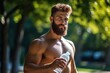 A young bearded man does sports in nature. Healthy lifestyle concept. Guy with a bottle of water after a workout in a summer park.