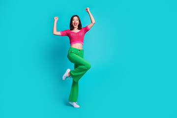 Sticker - Full size photo of overjoyed girl wear pink knit top green trousers raising hands up yell win gambling isolated on blue color background