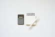 Black calculator, notepad, pen on white desk background. flat lay, top view