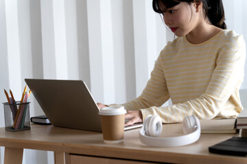 Sticker - A young woman sitting at a table using a laptop