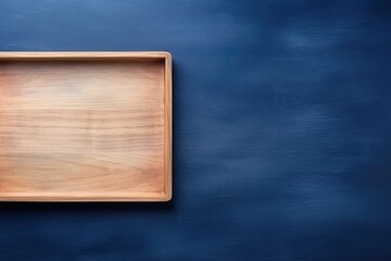 Poster - Rectangular wooden tray empty on textured dark blue table, in top view as a minimal kitchen flat lay.