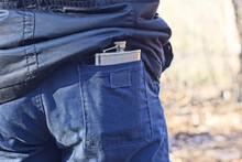 One White Metal Flask With Alcohol In A Blue Pants Pocket On A Man On The Street