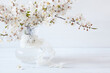 Blooming cherry plum branches in a vase on a white wooden table, copy space, blur, selective focus
