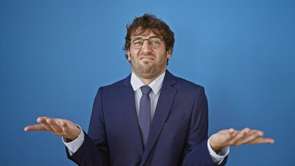 Sticker - Young, clueless man in business suit, undecided with arms wide on isolated blue background, expressing 'no idea' concept in bewilderment