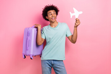 Canvas Print - Photo of cool excited guy wear blue t-shirt rising baggage holding paper plane empty space isolated pink color background