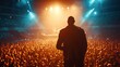 © Oleksii - A performer is standing on stage with their back to the camera, facing a large crowd under bright stage lights.