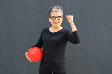 Poster - Active and healthy mature woman with a ball, enjoying a fitness workout in the park, radiating strength and happiness.