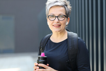 Wall Mural - Smiling woman, holding a water bottle, radiates health and happiness in her active and athletic lifestyle.