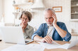 © InsideCreativeHouse - Depressed sad concentrated senior old elderly couple dealing with documents, solving financial problems, feeling confused while receiving mortgage loan contract at home kitchen