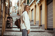 A young attractive blonde woman tourist walks through the streets of a European city.