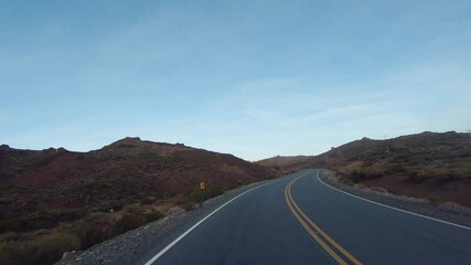 Wall Mural - Journey. Point of view of a car driving along the road in the Andes mountains and desert at sunset.