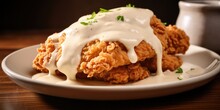 This Enticing Food Shot Focuses On A Decadent Plate Of Crispy Fried Chicken Smothered In A Creamy, Tangy White Gravy, Creating A Harmonious Blend Of Flavors That Will Leave You Craving For
